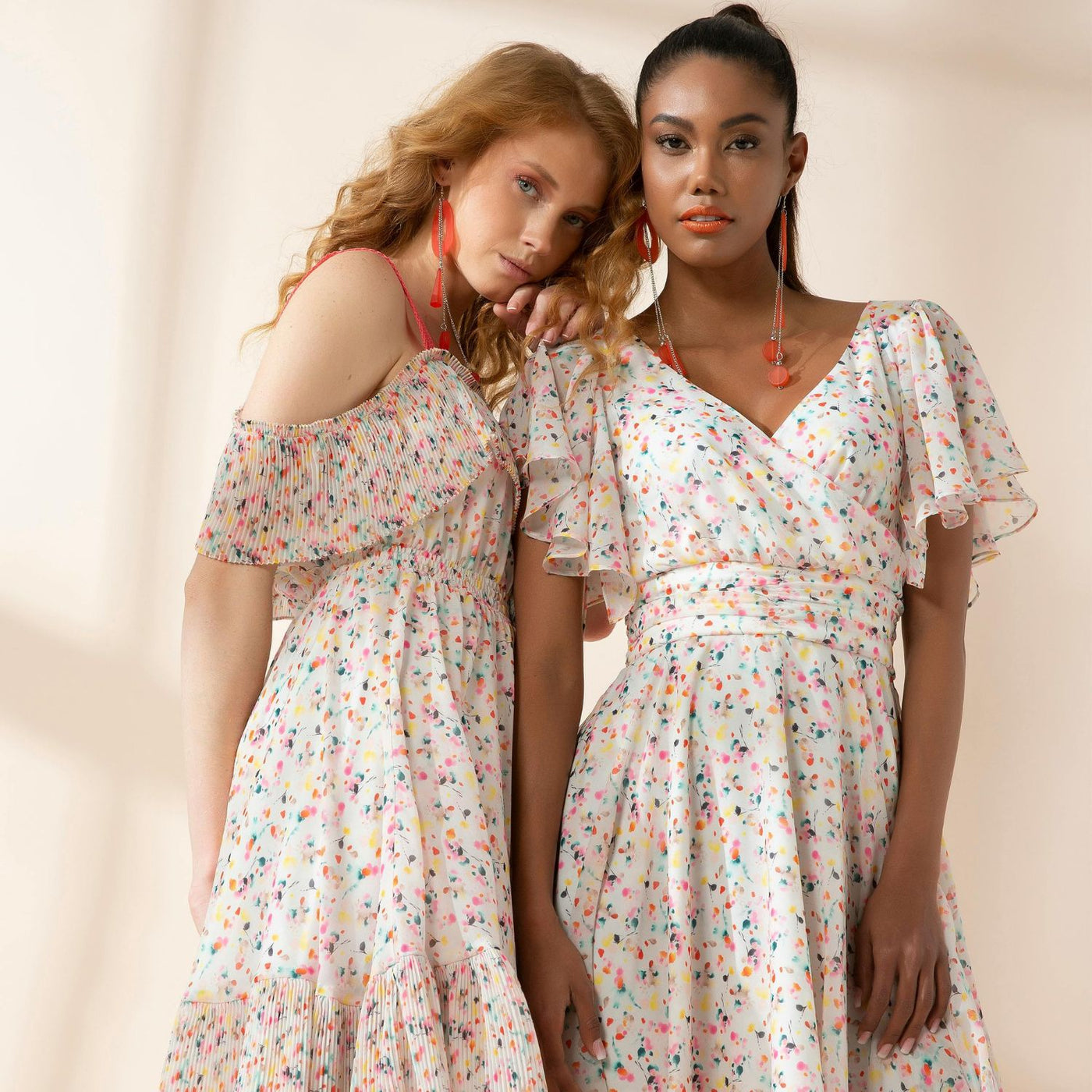 Two girls wearing dresses against pastel coloured wall